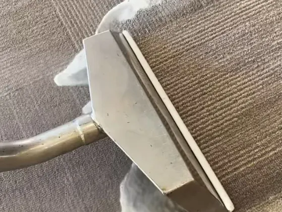 Close-up of a carpet cleaning wand pulling a clean stripe through the carpet
