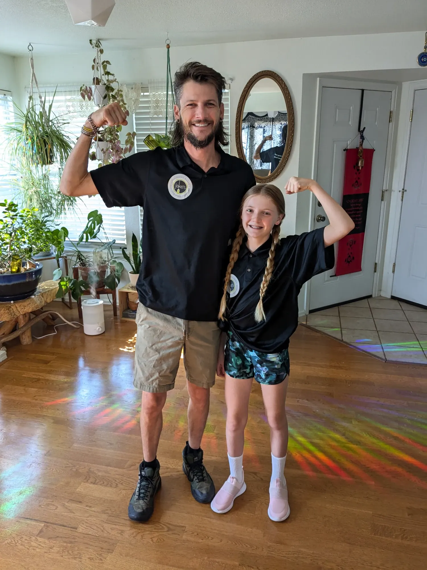 Jake and his daughter flexing their arms in a sunny living room