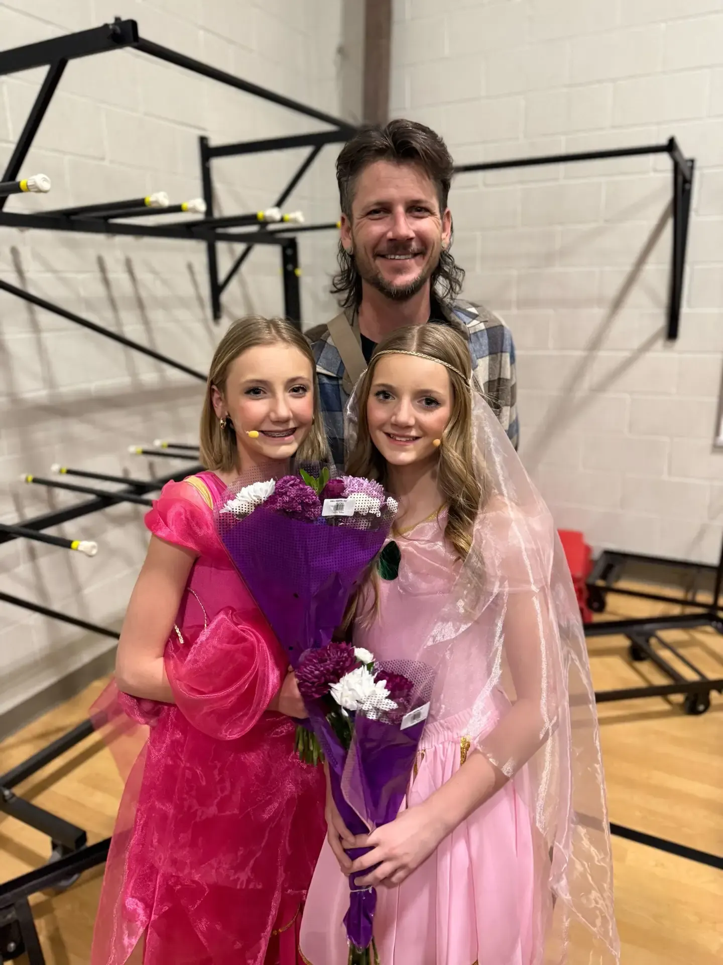 Jake with his two daughters in pink dance costumes after a recital