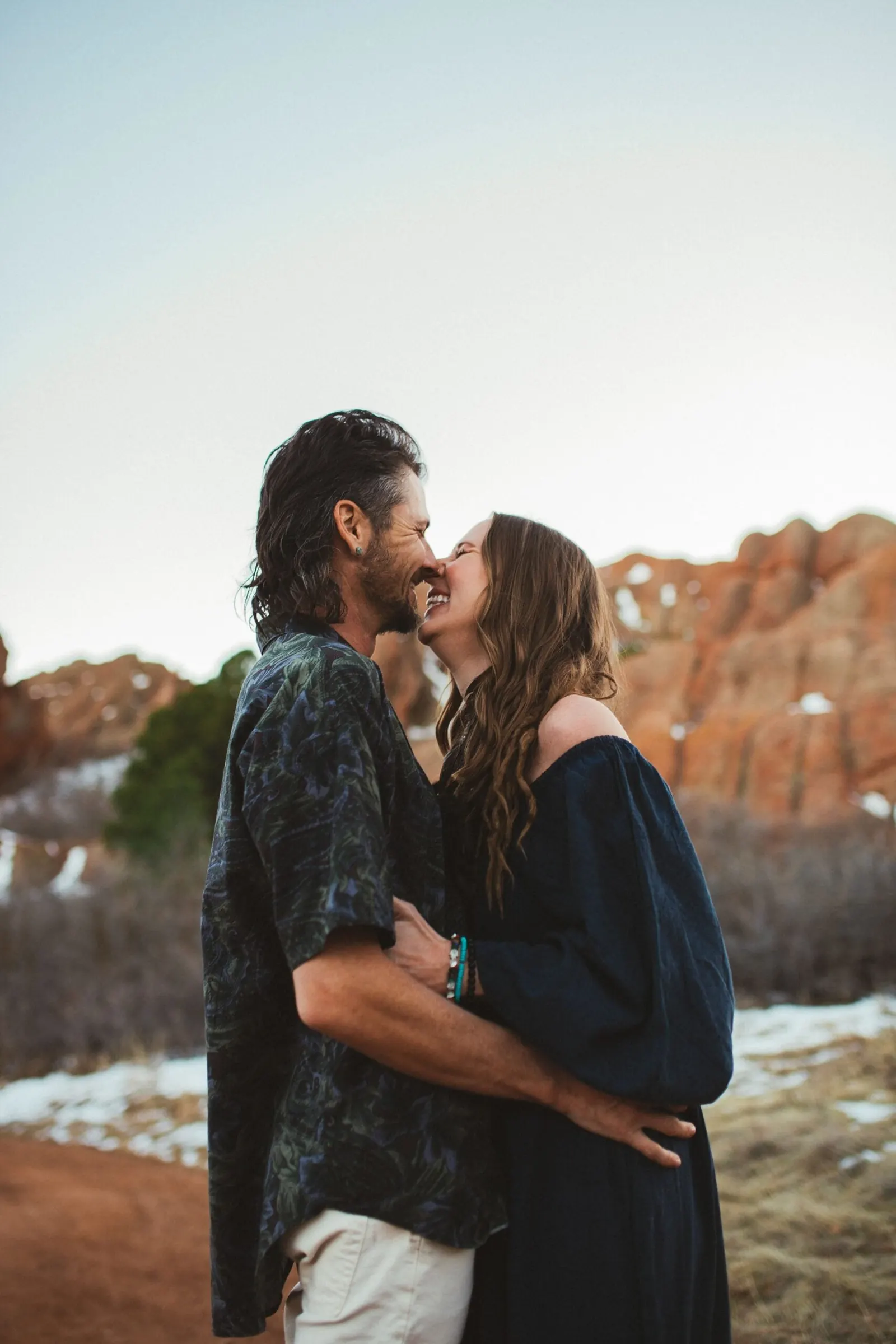 Jake kissing his wife against a winter sky and red rocks