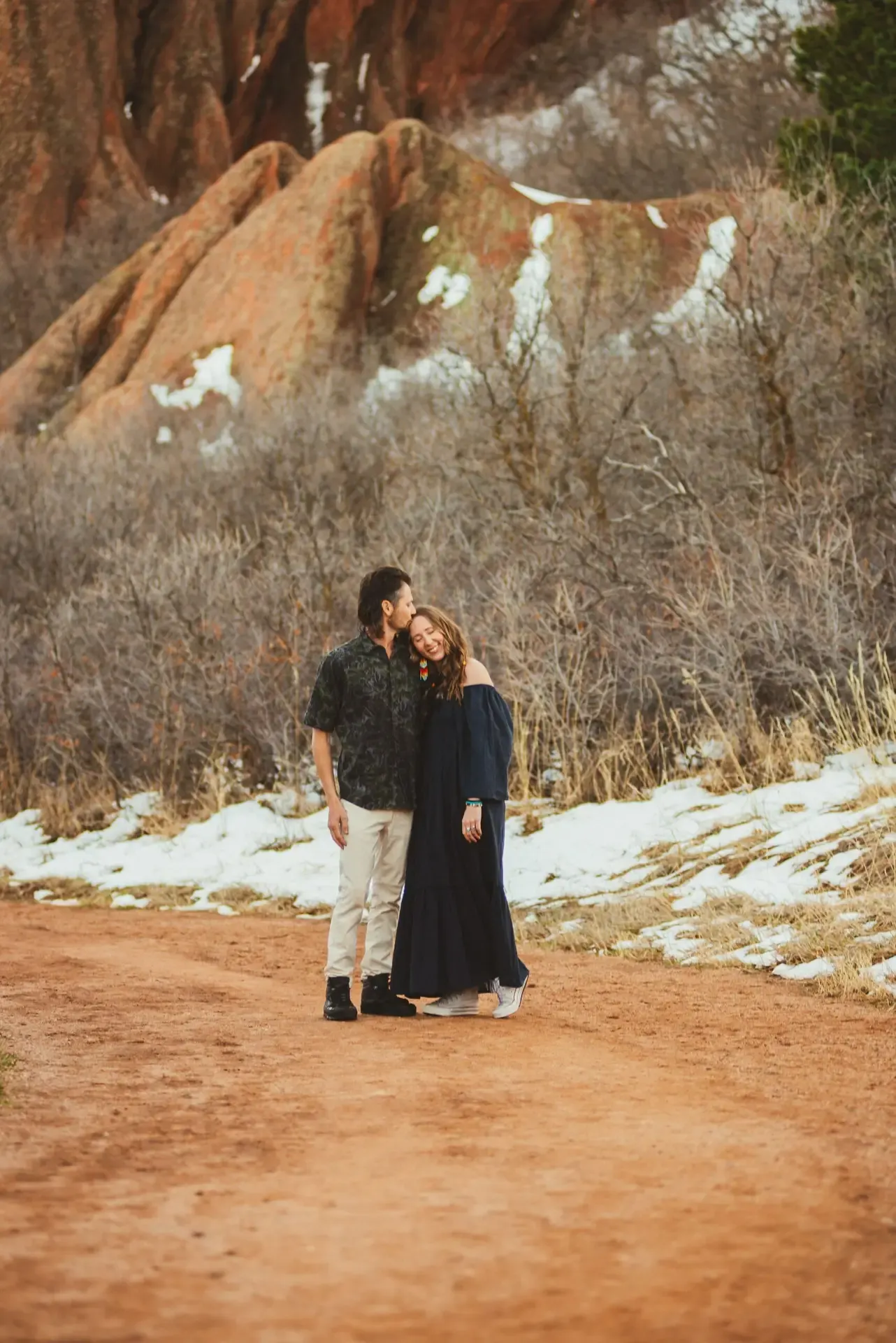Jake and his wife standing close among the red rock formations