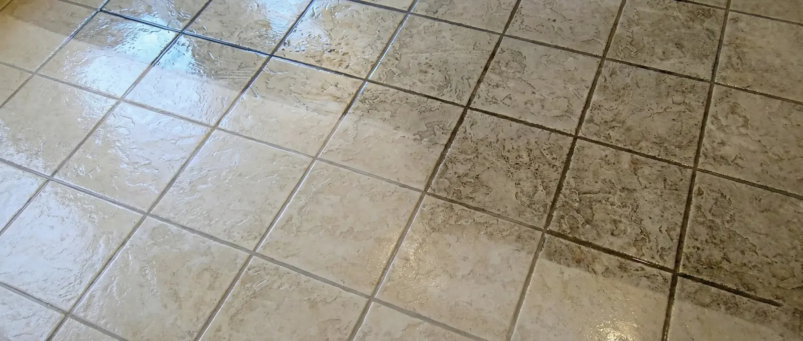 A tile floor mid-cleaning: freshly cleaned light grout lines beside dark, dirty ones